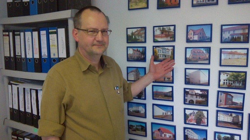 Ulf Zaspel in seinem Büro vor der Wand mit Sehenswürdigkeiten von Städten, die er per Video präsentiert (Foto: Kurt Frank)