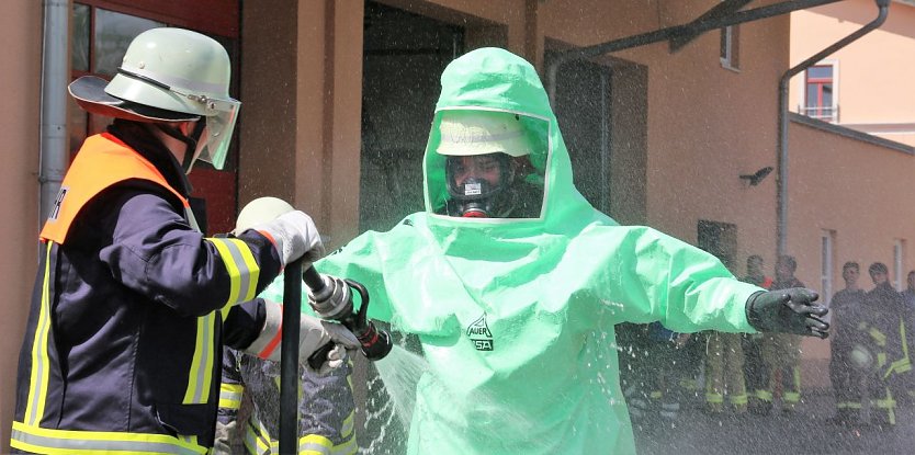 Ein Feuerwehrmann im Schutzanzug wird zu &Uuml;bungszwecken dekontaminiert. (Foto: Susanne Schedwill)