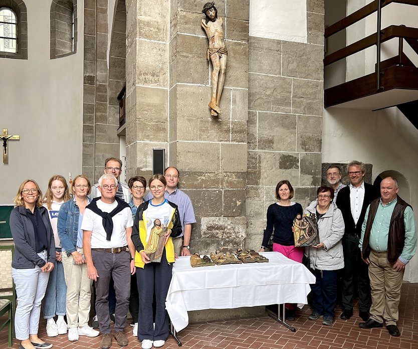 Die Gemeinde freut sich, das Kruzifix wieder in der Kirche zu wissen. B&auml;rbel Treutler vom Gemeindekirchenrat h&auml;lt die restaurierte Altartafel in H&auml;nden, die damals ebenfalls zerbrochen ist. Pfarrer Klemens M&uuml;ller (im Anzug) steht rechts neben ihr. Den Vorsitzenden des Gemeindekirchenrates, Ralf Schumann, finden Sie links neben dem Tisch, hinten im hellblauen Hemd (Foto: Steffen Mund)