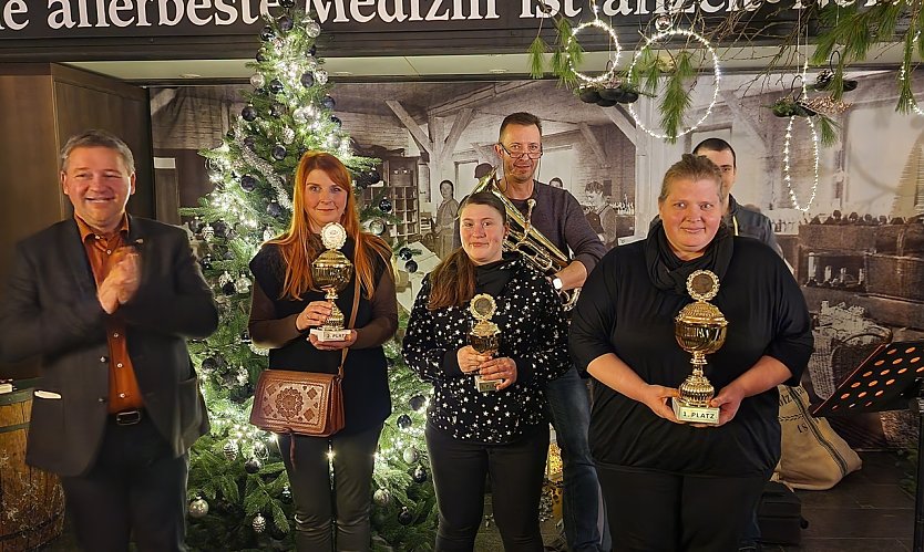 Die Siegerinnen des diesj&auml;hrigen Adventskranzwettbewerbes, links Thomas M&uuml;ller, dahinter die beiden Musiker des Abends (Foto: nnz)