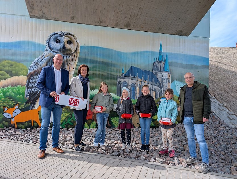 Iva, Eva, Maila und Zoey von der Grundschule Hohenbra pr&auml;sentierten B&uuml;rgermeister Steffen Grimm (links), Landr&auml;tin Antje Hochwind-Schneider (2.v.li.) und Deutsche Bahn-Projektleiter Marco Kresse (rechts) stolz ihre selbst entworfenen Bilder am Br&uuml;ckenpfeiler (Foto: Janine Skara)