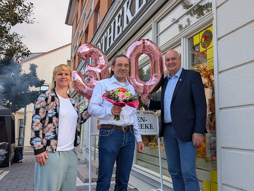 Citymanagerin Kathrin Kilian (li.) und B&uuml;rgermeister Steffen Grimm (re.) gratulierten Thomas Wi&szlig;gott zum 30. Geburtstag der Loewen-Apotheke. (Foto: Janine Skara)