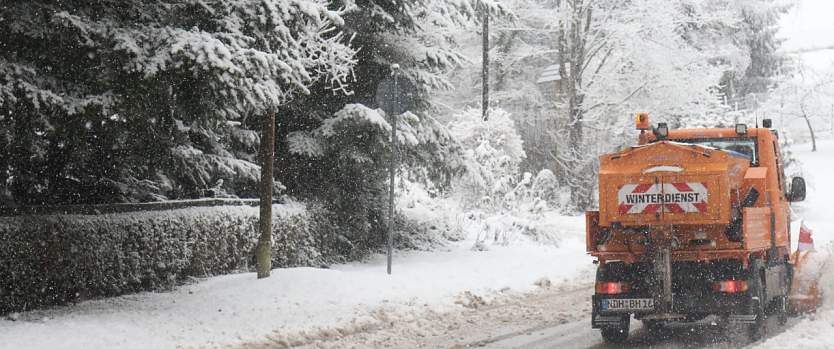 Bild: Ein Schneepflug ist auf einer verschneiten Stra&szlig;e unterwegs.