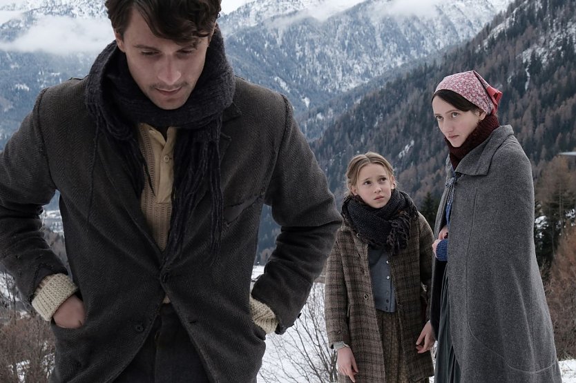 Bild: Ein Mann, eine Frau und ein M&auml;dchen stehen in einer Bergkulisse. 
