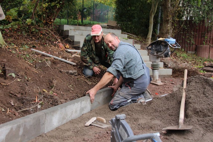 Bild: &ouml;rg Blank und Helmut Riechel (rechts) von der Firma GAI aus Niedersachswerfen beim Einsetzen der Borde f&uuml;r die neue Treppenanlage an der K&auml;the-Kollwitz-Schule.
