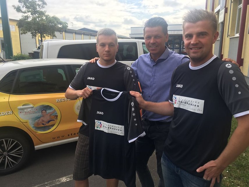 Bild: Jens Eisenschmidt von den Stadtwerken Nordhausen, &uuml;bergab T-Shirts mit Unternehmenslogo an die Mitarbeiter Torsten Sch&ouml;nleiter und Martin Hohl