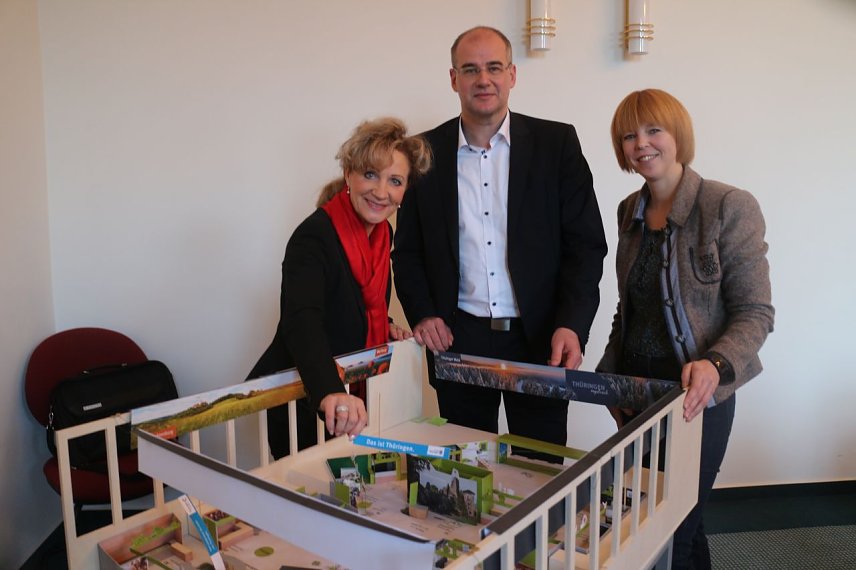 Bild: v.l.: Ministerin Birgit Keller, Landrat Matthias Jendricke und Jessica Pieper vor dem Modell des Th&uuml;ringer Messeauftritts