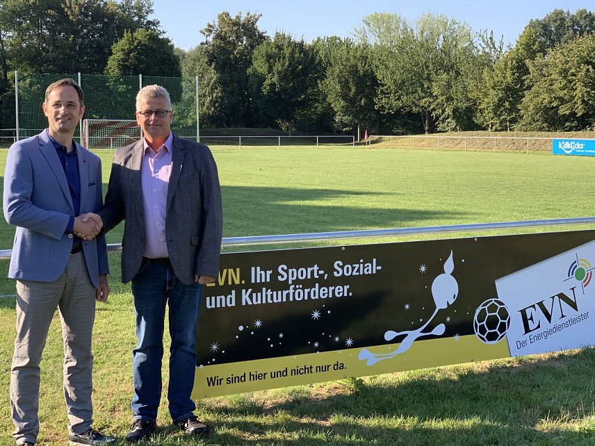 Bild: Dirk Mei&szlig;geier (EVN) und Ortsteilb&uuml;rgermeister Michael Kramer (von links) bei der &Uuml;bergabe der EVN-Werbetafel auf dem Hesser&ouml;der Sportplatz