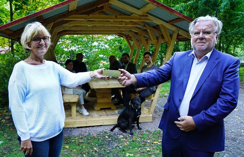 Bild: Ortschaftsb&uuml;rgermeisterin Petra Gerlach und Christian M&ouml;hrmann von der Hellbuth GmbH mit der Spenderplakette, die an die neue Wandersitzgruppe  in Ilfeld montiert worden ist