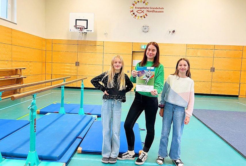 Bild: Schulleiterin Tina Kallmeyer freut sich &uuml;ber den 1. Platz beim Kreisfinale im Crosslauf mit den L&auml;uferinnen Ellie Marie Lange und Paula Laurie Hilger der Klasse 4a. 