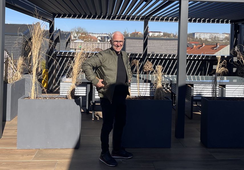 Bild: Axel Heck strahlt mit der Sonne um die Wette auf seiner neuen Terrasse inmitten der "tiny houses"