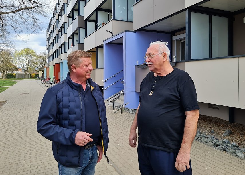 Bild: Projektleiter Steffen Peter (links)  im Gespr&auml;ch mit Mieter Hartmut Schibb. Er freut sich &uuml;ber den Anschluss der Sanierungsarbeiten in dem Block im Zuckerweg 5-19