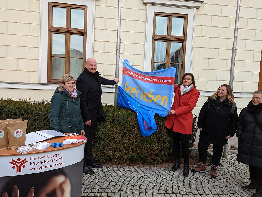 Bild: andr&auml;tin Antje Hochwind-Schneider (3.v.re.) und B&uuml;rgermeister Steffen Grimm (2.v.li.) hissen beim Aktionstag gegen h&auml;usliche Gewalt die Flagge als Symbol f&uuml;r die gemeinsame Zusammenarbeit gegen Gewalt an Frauen und M&auml;dchen im Kyffh&auml;userkreis.