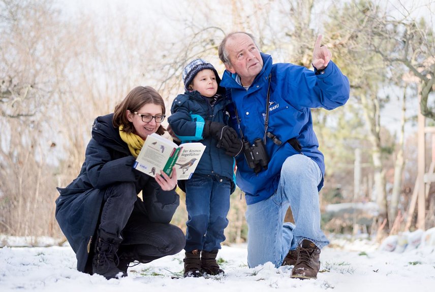 Bild: Eine Frau, ein Mann und ein Kind in einer Winterlandschaft. Sie z&auml;hlen Winterv&ouml;gel. 