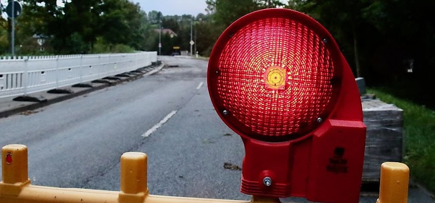 Bild: Eine rote Warnleuchte und eine gesperrte Stra&szlig;e. 