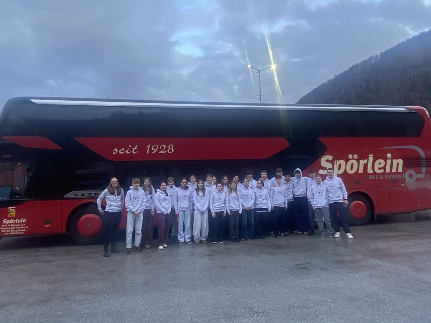 Bild: Eine Gruppe Sch&uuml;ler vor einem Reisebus in den Alpen