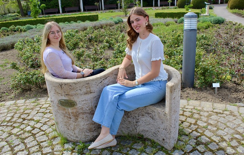 Bild: Zwei junge Frauen auf einer Bank im Rosengarten