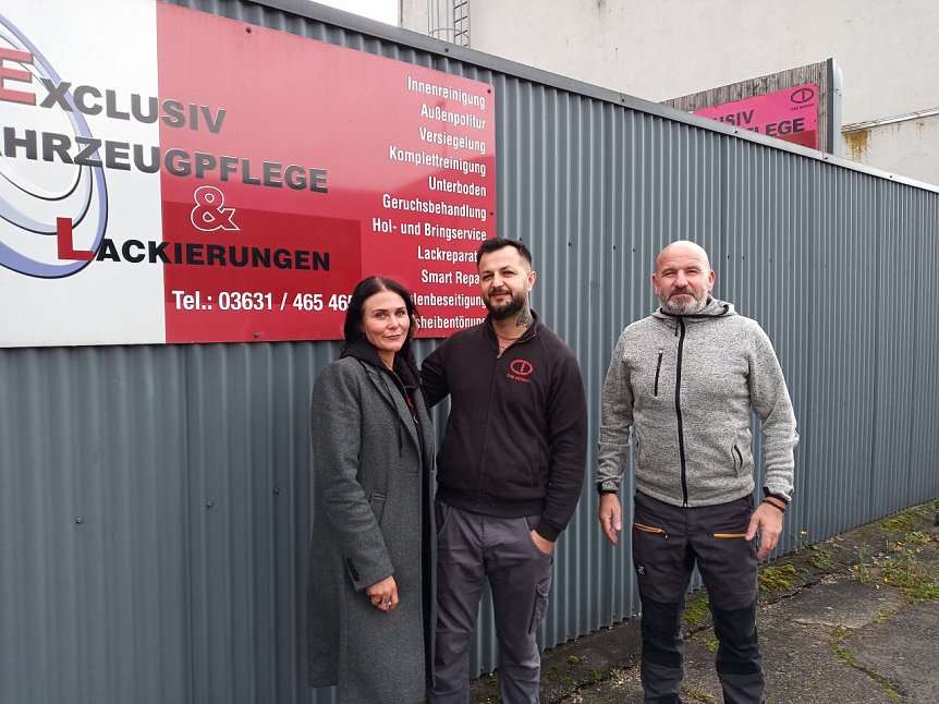 Bild: Theresa Stobbe, Buchhalterin bei CAR DESIGN, Shamsul Ahmadi und Filialleiter Axel Kaiser vor dem Firmenlogo.