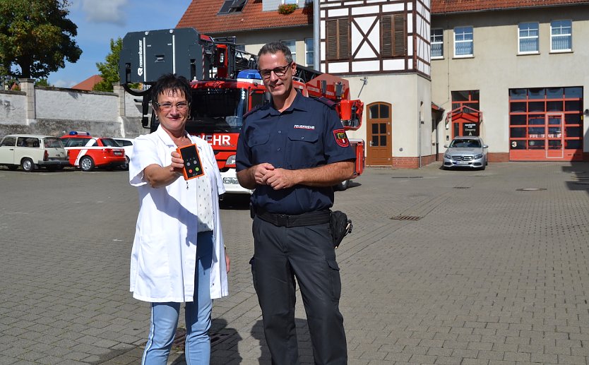Elisabeth Ringleb, Pharmazie-Ingenieurin der Br&uuml;cken-Apotheke M&uuml;hlhausen, &uuml;bergab das Messger&auml;t an Hauptbrandmeister Martin Schmidt von der Feuerwehr M&uuml;hlhausen. (Foto: Anke Pfannstiel &copy; Stadtverwaltung M&uuml;hlhausen)