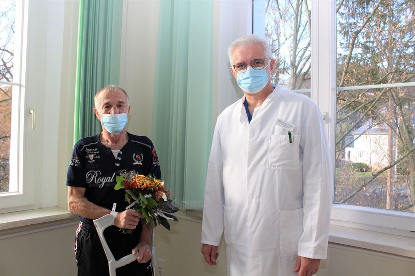 Uwe Lachmann (li). erhielt während seines Aufenthaltes nicht nur ein neuen Hüftgelenk von Chefarzt Dr. med. Steffen Kohler (re.), sondern beim Verlassen der Helios Klinik Bleicherode auch einen Blumenstrauß. (Foto: Janine Skara)