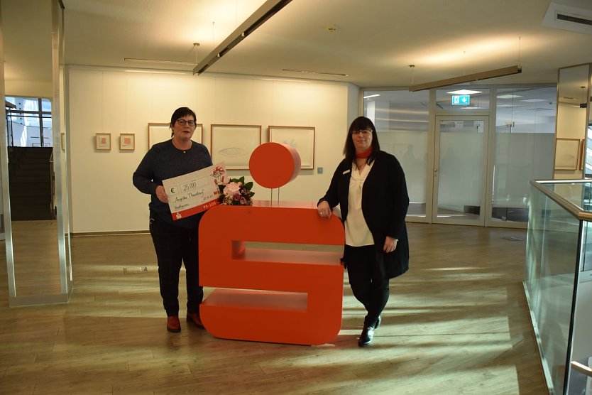 Kundenberaterin Yvonne Dennstedt &uuml;berreicht der gl&uuml;cklichen Gewinnerin einen symbolischen Scheck und Blumen. (Foto: Kreissparkasse Nordhausen)