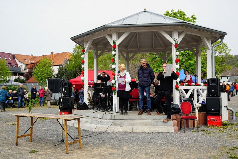 Ortschaftsbürgermeisterin Petra Gerlach und Ortschaftsrat  Matthias Mügge präsentieren das Sponsorenschild. Ein Großteil der 65 Spender hatte sich zum Foto unter dem Maibaum eingefunden. (Foto: Susanne Schedwill )