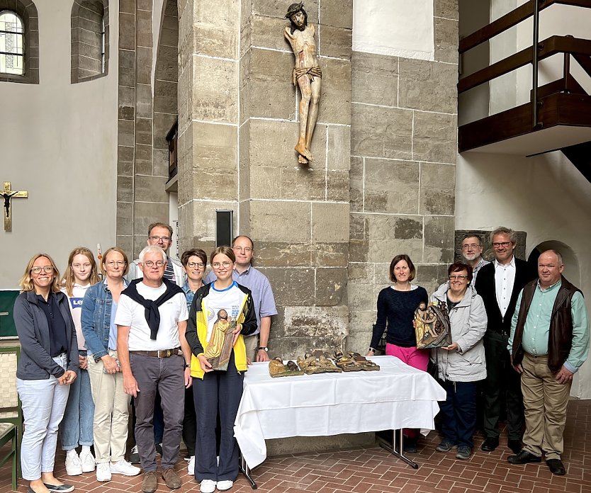 Die Gemeinde freut sich, das Kruzifix wieder in der Kirche zu wissen. Bärbel Treutler vom Gemeindekirchenrat hält die restaurierte Altartafel in Händen, die damals ebenfalls zerbrochen ist. Pfarrer Klemens Müller (im Anzug) steht rechts neben ihr. Den Vorsitzenden des Gemeindekirchenrates, Ralf Schumann, finden Sie links neben dem Tisch, hinten im hellblauen Hemd (Foto: Steffen Mund)