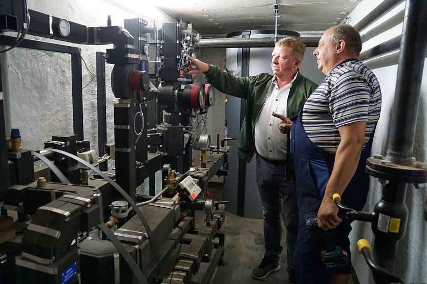 Installateur Mike Burgkardt (vorn) von der Firma Badmanufaktur Eberhardt aus Nordhausen erläutert Steffen Peter von SWG die neue Fernwärmeübergabe- und Verteilstation, die idemnächst in Betrieb geht. (Foto: SWG/S.Schedwill)