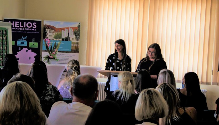 Die Absolventinnen Mareike Thöner (links) und Jennifer Werle (rechts) verabschieden sich von Lehrkräften, Praxisanleiter:innen und weiteren Beteiligten an der Ausbildung (Foto: Fotocredit: Helios Kliniken Mansfeld-Südharz GmbH | Antonia Bütof )