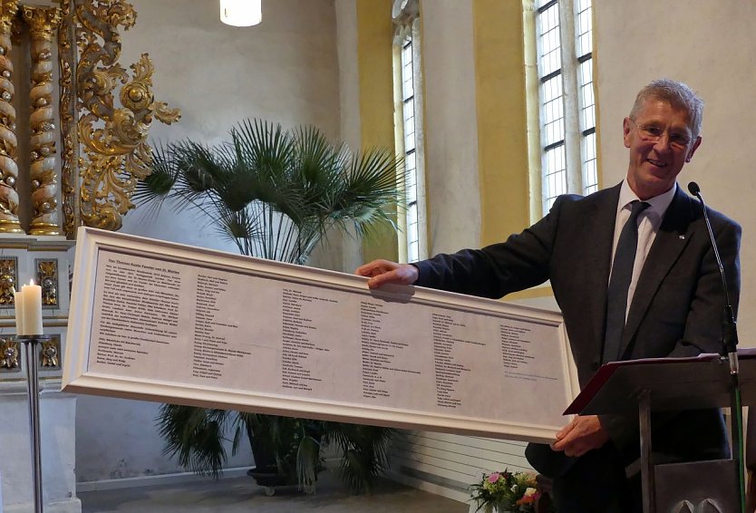 Dr. Christoph Maletz präsentiert die Spendertafel, die kurz darauf unter dem Fenster ihren Platz findet (Foto: Evangelischer Kirchenkreis Südharz)