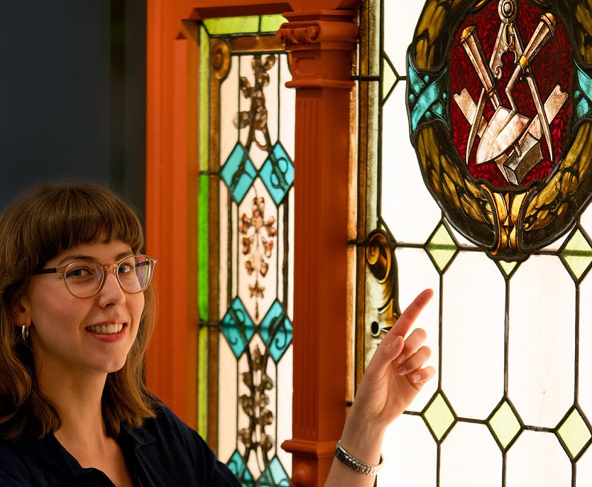 Am kunstvoll gearbeiteten Fenster erklärt Sarah Pönicke die Symbole und deren Bedeutung für die Freimaurer. (Foto: Alexander Hartleib | Mühlhäuser Museen)