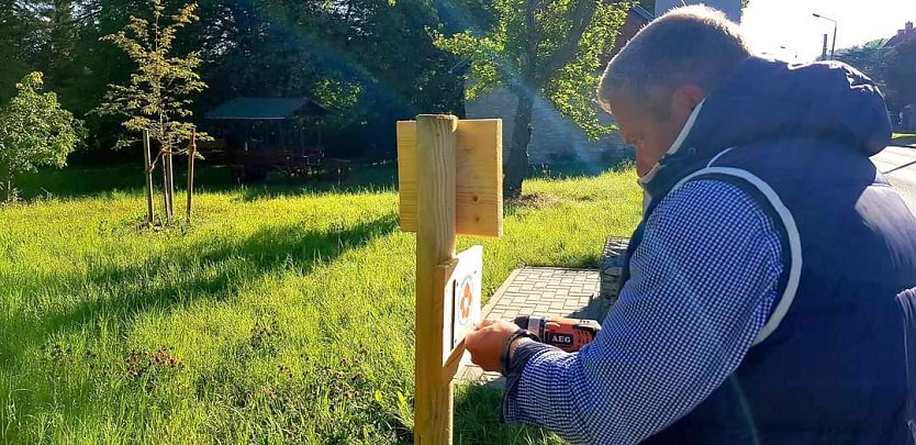 Ortschaftsbürgermeister Magnus Englert bringt die Beschilderung an der Wegekapelle an. (Foto: Evangelischer Kirchenkreis Südharz)