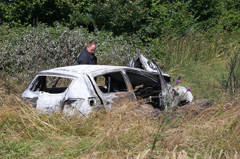 Polizisten untersuchen das ausgebrannte Wrack eines Dacias an der Unglücksstelle (Foto: S.Dietzel)